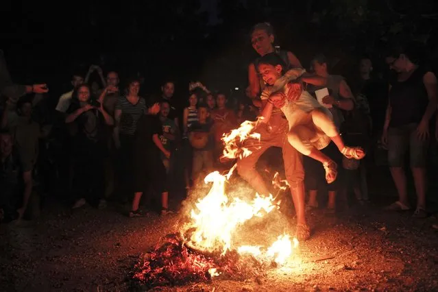 A woman helps a girl cross a fire as part of a traditional custom during the annual Klidonas event that takes place on the eve of the feast of Saint John the Baptist, in Athens June 23, 2014. (Photo by Alkis Konstantinidis/Reuters)