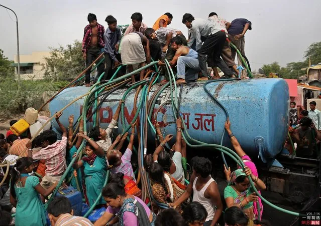 Residents crowd a government tanker delivering drinking water in New Delhi, India, on July 6, 2012. A patchy monsoon season has left many residents scrambling for water. (Photo by Kevin Frayer/AP)