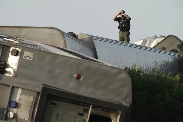 A law enforcement officer inspects the scene of an Amtrak train which derailed after striking a dump truck Monday, June 27, 2022, near Mendon, Mo. (Photo by Charlie Riedel/AP Photo)