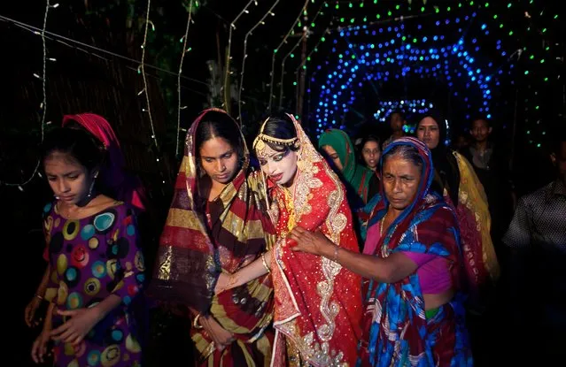 Nasoin Akhter, 15, is led by relatives to a car that will take her to her new home on the day of her wedding to a 32-year-old man, August 20, 2015, in Manikganj, Bangladesh. (Photo by Allison Joyce/Getty Images)