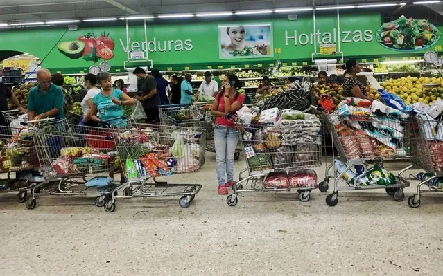 People queue with full carts at a supermarket in Cali, Colombia on March 18, 2020. Nine Latin American countries have coordinated to protect themselves and counteract the effects of the new coronavirus, in a region where seven people infected have already died and where borders have been closed, increasingly restricting the mobility of people. (Photo by Luis Robayo/AFP Photo)