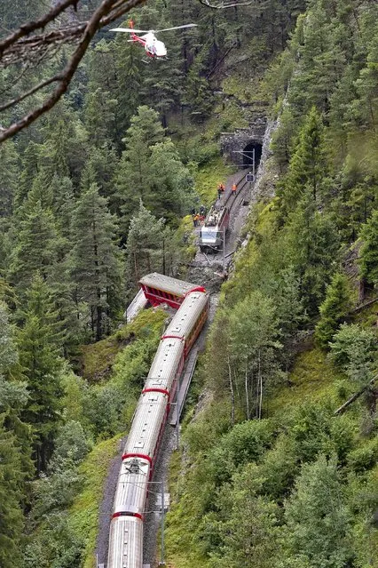 A helicopter flies over a train after it was derailed by a landslide near Tiefencastel, in a mountainous part of eastern Switzerland, on August 13, 1014. A landslide derailed a passenger train in the Swiss mountains on August 13 sending one carriage plunging into a ravine but it appeared that miraculously there had been no deaths. (Photo by Michael Buholzer/AFP Photo)