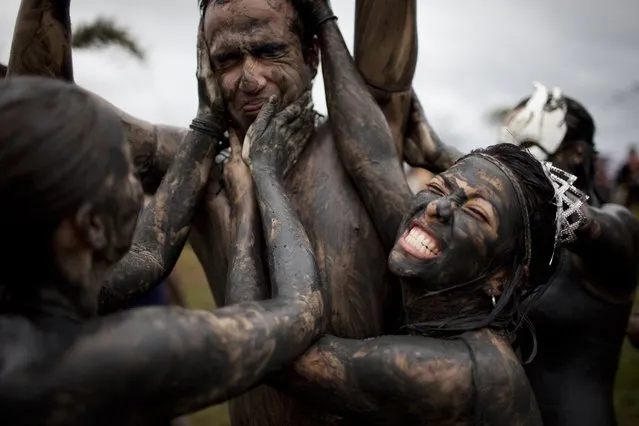 Women put mud over a man at a mud party during Carnival celebrations in Paraty,  Brazil, Saturday, March 5,  2011. (Photo by Rodrigo Abd/AP Photo)