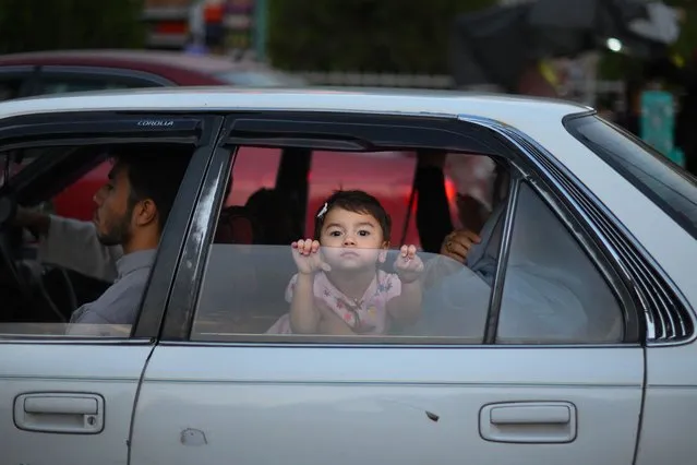 A little girl looks out the window of a car in Kabul on july 24, 2022. (Photo by Daniel Leal/AFP Photo)