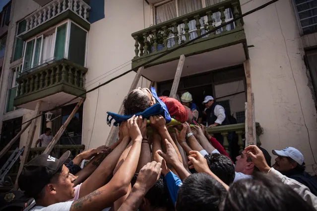 Rescuers and residents assist an injured victim amid the ruins of a building knocked down by a magnitude 7.1 earthquake that jolted central Mexico damaging buildings, knocking out power and causing alarm throughout the capital on September 19, 2017 in Mexico City, Mexico. The earthquake comes 32 years after a magnitude-8.0 earthquake hit on September 19, 1985. (Photo by Pedro Mera/Getty Images)