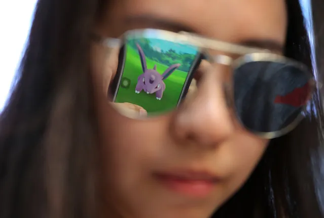 A mobile screen is reflected on a fan's sunglasses as she plays “Pokemon Go” in Hong Kong, Monday, July 25, 2016. Pokemon fans participated in creatures hunting on Monday as the app was released to both iPhone and Android users. (Photo by Kin Cheung/AP Photo)