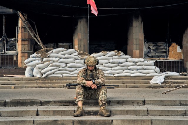 A Ukrainian soldier takes a rest on the steps of the City Hall in Izium, Kharkiv region, Ukraine, Tuesday, September 13, 2022. (Photo by Kostiantyn Liberov/AP Photo)
