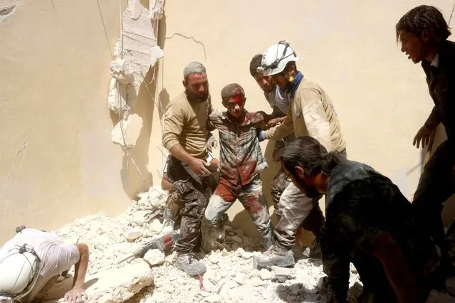 Syrian civil defence workers rescue a wounded young man from under the rubble of a collapsed building following reported air strikes on July 17, 2016 in the rebel-controlled neighbourhood of Maysar in the northern Syrian city of Aleppo. Opposition-controlled parts of Syria's battered northern city Aleppo came under total siege, after government forces severed the last route out of the east. An estimated 300,000 civilians live in rebel-held neighbourhoods of Syria's second city, according to the United Nations, and there are fears that they could face starvation. (Photo by Thaer Mohammed/AFP Photo)