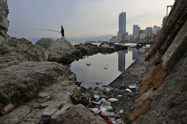 In this Wednesday, November 14, 2018 photo, a man casts his fishing pole in the Mediterranean Sea as trash are seen on a rocky coastal area along the Beirut coastline, Lebanon. Fisherman Ahmad Obeitri, who has been a fixture at Lebanon’s corniche for the past 30 years, says the trash is killing off what’s left of marine life. “These days if a fish comes our way it will only find nylon bags, garbage and sewage to feed on”, he said, lamenting the people who eat and drink as they walk on the corniche and then toss their cans, tins and other containers in the sea. “You can open a cafe under water and invite your friends”, he adds sarcastically. (Photo by Hassan Ammar/AP Photo)