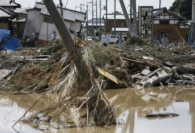Local residents walk near the site where destroyed street and electric power poles are seen, at a residential area flooded by the Kinugawa river, caused by typhoon Etau, in Joso, Ibaraki prefecture, Japan, September 11, 2015. (Photo by Issei Kato/Reuters)