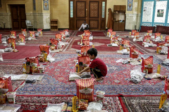 A boy is seen near to prepared food packages to be distributed to poor families during the holy month of Ramadan, following the outbreak of the coronavirus disease (COVID-19), in Tehran, Iran, April 30, 2020. (Photo by Ali Khara/WANA (West Asia News Agency) via Reuters)