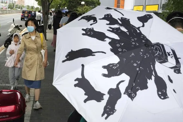 A woman wearing a mask passes an umbrella with a cat design in Beijing, Monday, October 3, 2022. (Photo by Ng Han Guan/AP Photo)