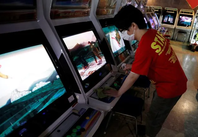 A staff member cleans a video game player with alcohol at the arcade game center Mikado in Tokyo, Japan on June 15, 2020. The arcade reopened last Friday after it had stopped business for 65 days amid the coronavirus disease (COVID-19) outbreak in Tokyo. (Photo by Kim Kyung-Hoon/Reuters)