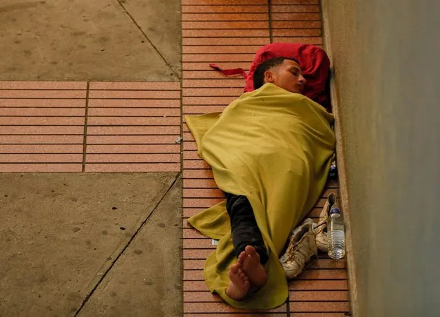 A Venezuelan migrant sleeps on the floor at a ramp of the Albrook Bus Terminal in Panama City on October 28, 2022. Stranded Venezuelan migrants request help from their embassy in Panama to enable humanitarian flights to return to Venezuela after a failed attempt to reach the United States. (Photo by Roberto Cisneros/AFP Photo)