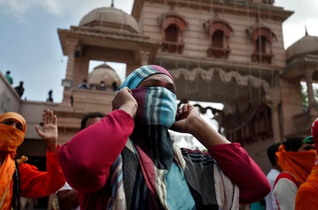 A Hindu devotee, with her face covered by a scarf, prays upon seeing a “Rath” or a chariot inside the premises of a temple during the annual Rath Yatra, or chariot procession, amidst the coronavirus disease (COVID-19) outbreak, in Ahmedabad, India, June 23, 2020. (Photo by Amit Dave/Reuters)