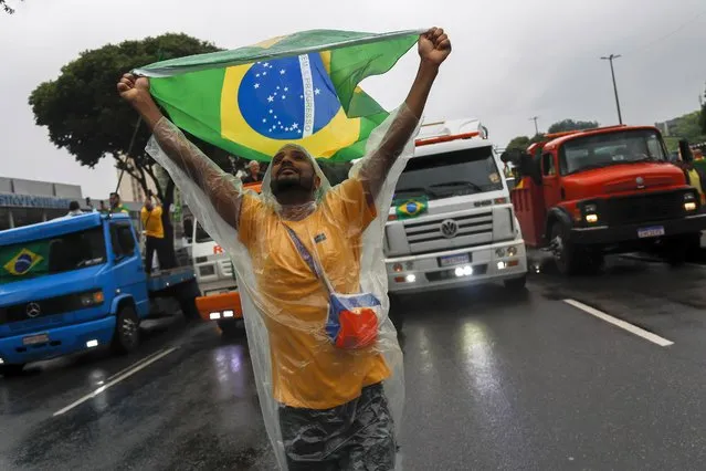 A supporter of President Jair Bolsonaro holds up a Brazilian national flag during a protest against his defeat in the presidential runoff election, in Rio de Janeiro, Brazil, Wednesday, November 2, 2022. Thousands of supporters called on the military Wednesday to keep the far-right leader in power, even as his administration signaled a willingness to hand over the reins to his rival Luiz Inacio Lula da Silva. (Photo by Bruna Prado/AP Photo)