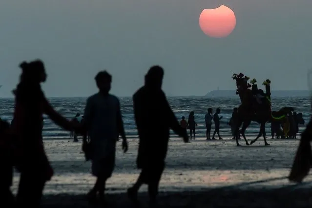 The moon partially obscures the sun during a partial solar eclipse visible on a beach from Karachi on October 25, 2022. (Photo by Asif Hassan/AFP Photo)