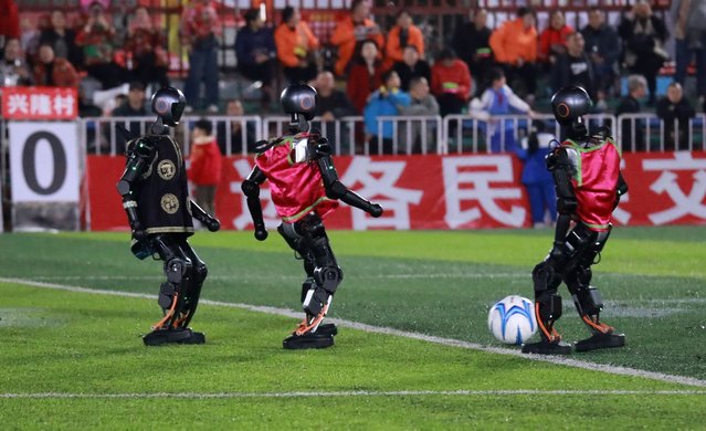 Humanoid robots dressed in traditional ethnic costumes compete in robot football match held in 'Village Super League' on March 14, 2025 in Rongjiang, Qiandongnan Miao and Dong Autonomous Prefecture, Guizhou Province of China. On the evening of March 14, an extraordinary event unfolded in Guizhou's “Village Super League” – a robot football match that captivated spectators with its uniqueness and technological prowess. (Photo by Yang Wenshu/VCG via Getty Images)
