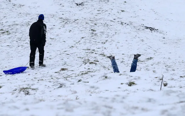 Families take to the hills with sledges near Edale in Derbyshire, northern England on December 10, 2017. Heavy snow fell across northern and central parts of England and Wales and caused disruption, closing roads and grounding flights at Birmingham airport. Up to 10cm is expected to build up quite widely, with 15-20cm in some spots, raising the prospect of roads becoming impassable. (Photo by Lindsey Parnaby/AFP Photo)
