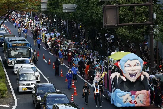 Participants wearing costumes walk behind a float during a Halloween parade in Kawasaki, south of Tokyo, October 26 2014. (Photo by Yuya Shino/Reuters)