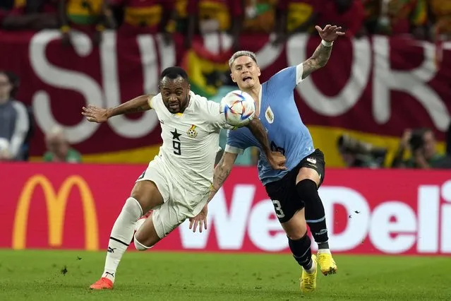 Ghana's Jordan Ayew, left, and Uruguay's Guillermo Varela fight for the ball during the World Cup group H soccer match between Ghana and Uruguay, at the Al Janoub Stadium in Al Wakrah, Qatar, Friday, December 2, 2022. (Photo by Themba Hadebe/AP Photo)