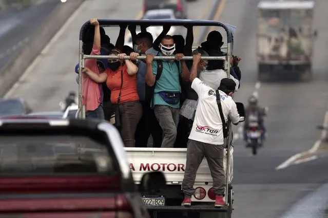 Commuters, wearing protective face masks, ride in the bed of a truck as public transportation has been temporarily suspended by the government in an effort to contain the spread of the new coronavirus, in San Salvador, El Salvador, Friday, August 7, 2020. For months, the strictest measures confronting the COVID-19 pandemic in Latin America seemed to keep infections in check in El Salvador, but a gradual reopening combined with a political stalemate has seen infections increase nearly fourfold. (Photo by Salvador Melendez/AP Photo)
