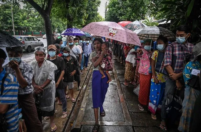 This photo taken on August 17, 2022, show people waiting in a queue to receive free meal along a street in Yangon. (Photo by AFP Photo/Stringer)