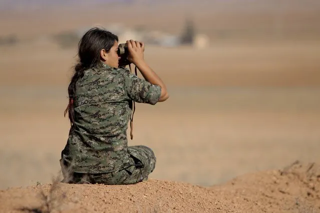 A female fighter of the Kurdish People's Protection Units (YPG) uses a pair of binoculars as she looks towards areas controlled by Islamic State fighters in the southern countryside of Ras al-Ain November 9, 2014. (Photo by Rodi Said/Reuters)