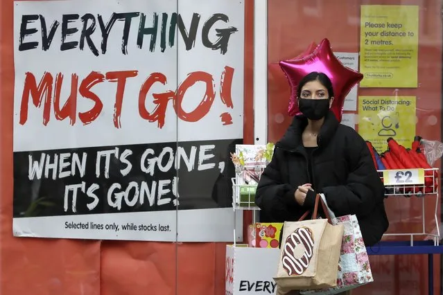 A shopper wears a mask as she exits a shop in Windsor, England, Wednesday, September 23, 2020. British Prime Minister Boris Johnson appealed Tuesday for resolve and a “spirit of togetherness” through the winter as he unveiled new restrictions on everyday life to suppress a dramatic spike in coronavirus cases. (Photo by Kirsty Wigglesworth/AP Photo)