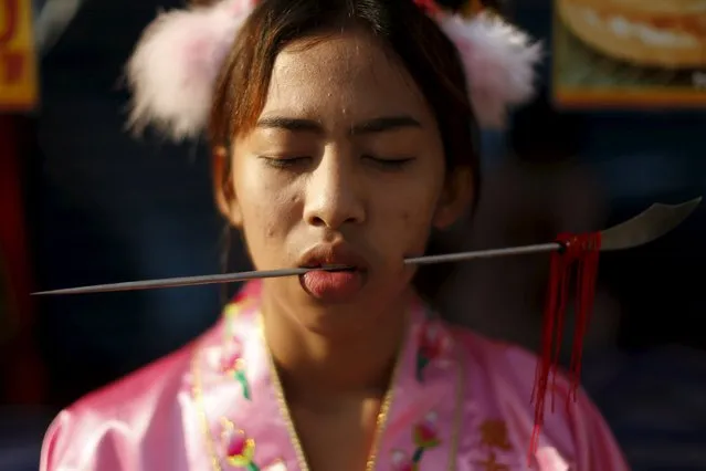 A devotee of the Chinese Jui Tui shrine walks with a spike pierced through her cheeks during a procession celebrating the annual vegetarian festival in Phuket, Thailand October 19, 2015. (Photo by Jorge Silva/Reuters)