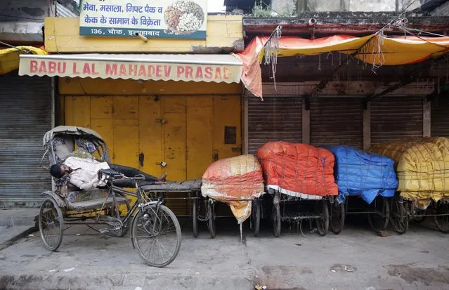 A rickshaw driver sleeps beside covered handcarts early morning in Allahabad, India, Tuesday, October 4, 2016. Some 800 million people in the country live in poverty, many of them migrating to big cities in search of a livelihood and often ending up on the streets. (Photo by Rajesh Kumar Singh/AP Photo)