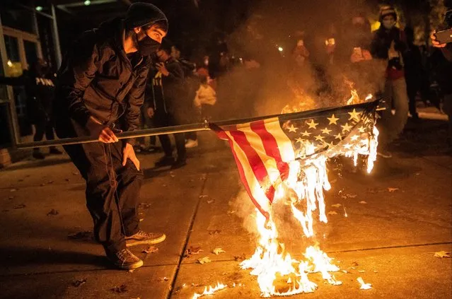 A protester burns an American Flag following a vigil for Kevin E. Peterson Jr., on October 30, 2020 in Vancouver, Washington. Clark County Sheriffs deputies shot and killed Peterson, 21, Thursday night, sparking city-wide dueling protests between Black Lives Matter activists and supporters of President Donald Trump. (Photo by Nathan Howard/Getty Images)