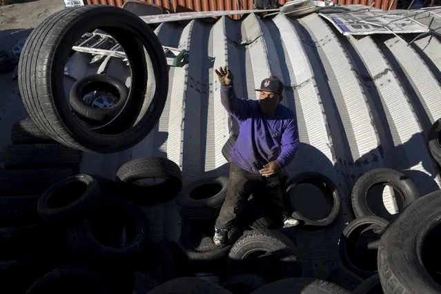 A worker reorganizes tires in the Willets Point area of Queens in New York October 26, 2015. (Photo by Andrew Kelly/Reuters)