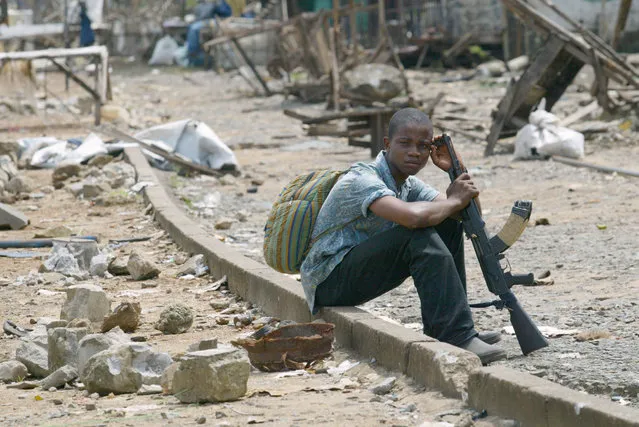 A young rebel of Liberians United for Reconciliation and Democracy (LURD) waits at the New Bridge in Monrovia August 9, 2003. (Photo by Juda Ngwenya/Reuters)