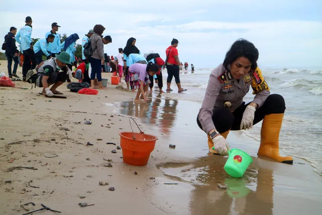 Policewomen with residents gather on the beach to clean the coast from the oil spilled at the Pantai Kilang Mandiri in Balikpapan, East Kalimantan, Indonesia on April 5, 2018, (Photo by Sheravim/Reuters/Antara Foto/UNI)