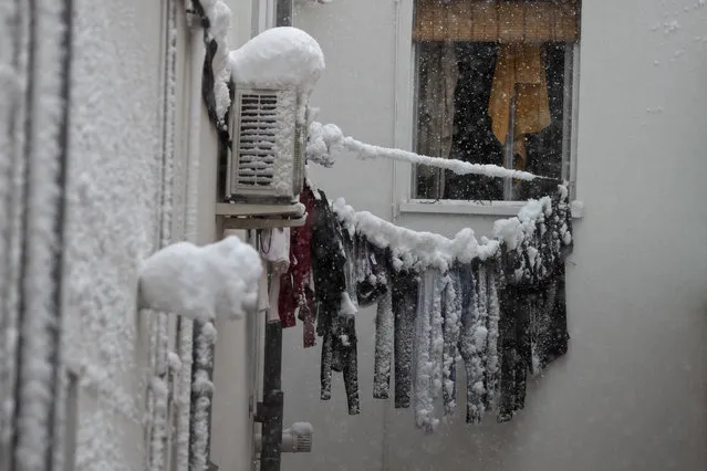 Frozen laundry hangs on a line outside an apartment window after a heavy snowfall in Madrid, Spain, Saturday, January 9, 2021. Spain is on high alert as a cold snap is covering much of the country with snow disrupting road, sea, rail and air traffic with the capital, Madrid enduring what the city's mayor described as “the worst storm in 80 years”. (Photo by Paul White/AP Photo)