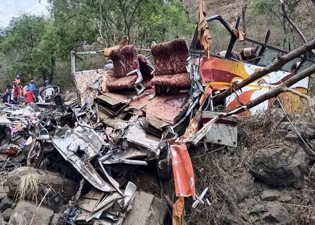 Police and rescue officials inspect the wreckage of a passenger bus near Khopoli, some 70 kilometres (43 miles) from Mumbai, India, Saturday, April 15, 2023. More than dozen passengers died and many injured after a bus fell into a gorge in Maharashtra's Raigad district, according to police official. The bus was carrying 42 passengers and was on its way to Mumbai from Pune. (Photo by AP Photo/Stringer)