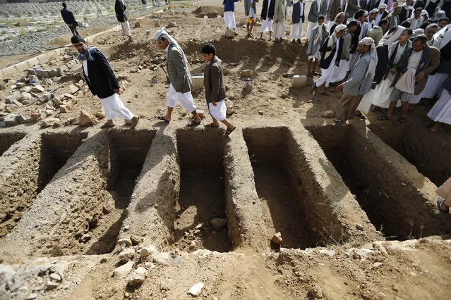 People walk past graves which were dug up for soldiers killed in the Wadi Hadramout region in northeastern Yemen, at a military cemetery in Sanaa August 10, 2014. (Photo by Khaled Abdullah/Reuters)