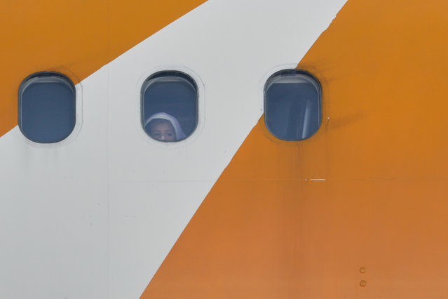 A child peers from a Venezuelan-operated plane arriving with deported migrants at Simon Bolivar International Airport in Maiquetia, Venezuela, Wednesday, December 3, 2025. (Photo by Cristian Hernandez/AP Photo)