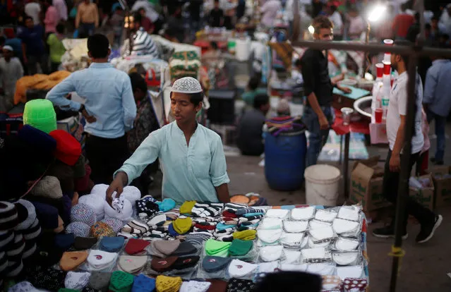 A boy looks at the skull caps before buying one on the eve of the holy fasting month of Ramadan, outside the Jama Masjid (Grand Mosque) in the old quarters of Delhi, India, May 16, 2018. (Photo by Adnan Abidi/Reuters)