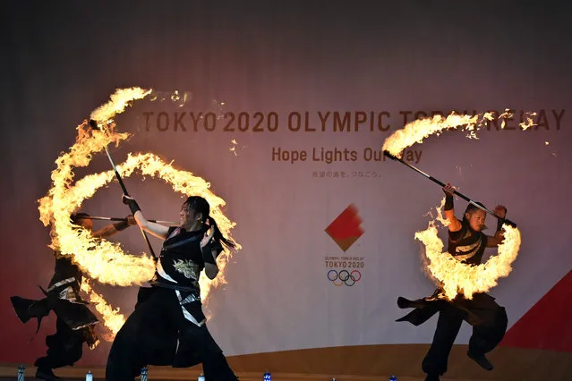Fire performers show their skills before the arrival of the torch bearer at Hibarigahara Festival Site, during the last leg of the first day of the Tokyo 2020 Olympic torch relay in Minamisoma, Fukushima Prefecture on March 25, 2021. (Photo by Charly Triballeau/AFP Photo)