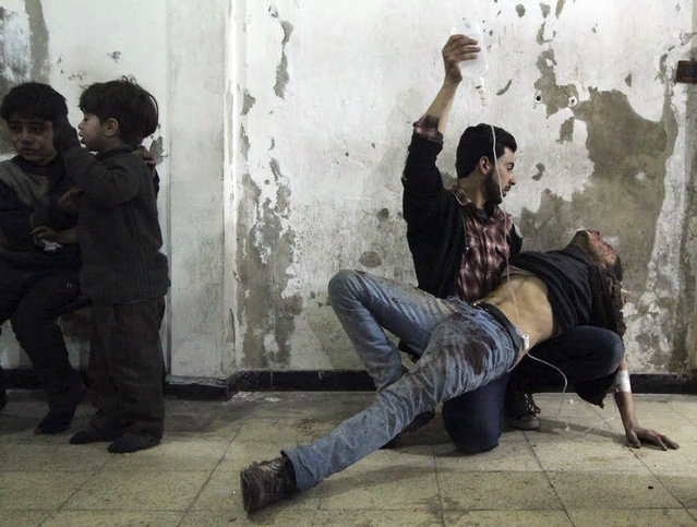 A man gives medical assistance to an injured man as two wounded children wait nearby at a field hospital after what activists said was an air strike by forces of Syria's President Bashar al-Assad in the Duma neighborhood of Damascus, February 2, 2015. (Photo by Mohammed Badra/Reuters)