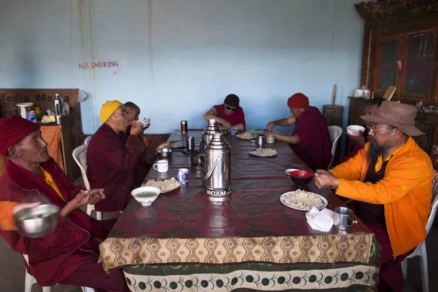 In this photograph taken on July 9, 2018, Indian Buddhist monks eat breakfast at the dining area after the morning “puja” at Tnagyud Gompa monastery in Komik in Spiti Valley in the northern state of Himachal Pradesh. (Photo by Xavier Galiana/AFP Photo)