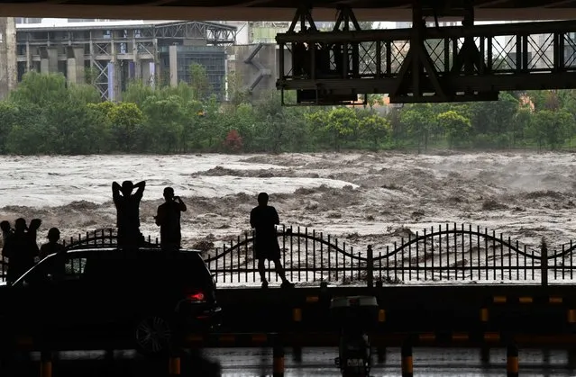 People look at the overflowing Yongding River following heavy rainfall in Beijing, China on July 31, 2023. (Photo by Reuters/China Daily)