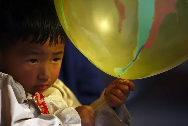 A Tibetan boy dressed in traditional attire holds a balloon as he observes the function organised to mark Losar or the Tibetan New Year at Tibetan Refugee Camp in Lalitpur February 19, 2015. (Photo by Navesh Chitrakar/Reuters)
