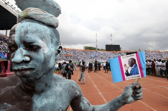 A supporter of Ivory Coast's President Laurent Gbagbo, also a presidential candidate for FPI “Ivorian Popular Front”, holds a poster of Gbagbo during his last campaign rally at the main stadium of Abidjan October 29, 2010. (Photo by Luc Gnago/Reuters)