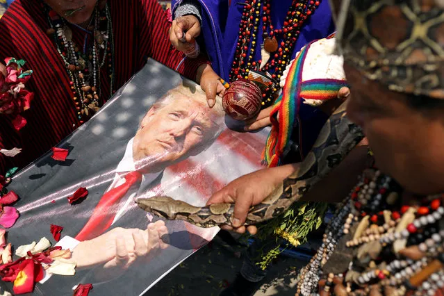 Peruvian shamans holding a poster of U.S. President Donald Trump and a boa constrictor snake perform a ritual of predictions for the new year at Pescadores beach in Chorrillos, Lima, Peru December 27, 2018. (Photo by Mariana Bazo/Reuters)