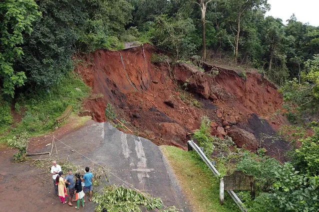 In this picture taken on July 26, 2021, onlookers gather near the site of a landslide due to ongoing heavy monsoon rains at Yellapur in the Uttara Kannada district of Karnataka. (Photo by Gopalkrishna Upadhyaya/AFP Photo)