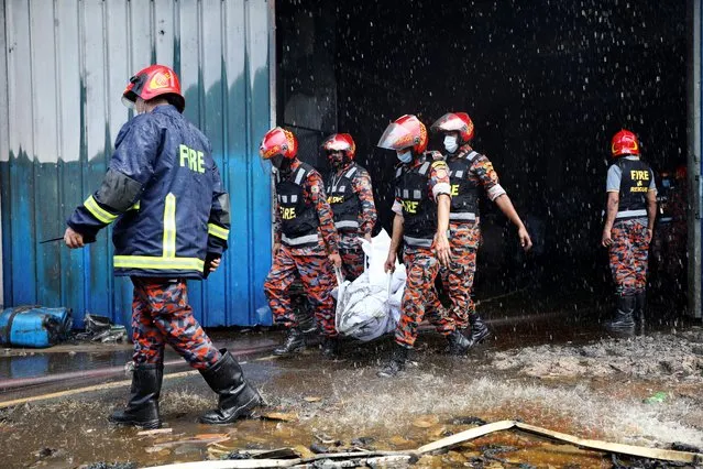 Rescue workers carry the bodies that were recovered after a fire broke out at a factory of Hashem Foods Ltd in Rupganj, Narayanganj district, on the outskirts of Dhaka, Bangladesh, July 9, 2021. (Photo by Mohammad Ponir Hossain/Reuters)