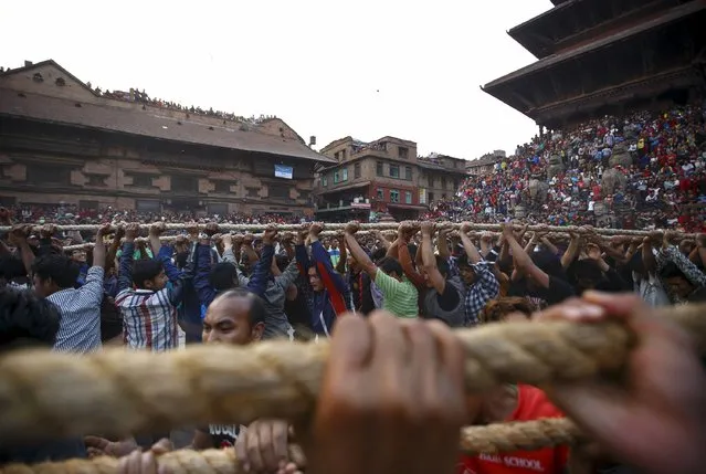 Devotees hold on to the ropes tied to the chariot of God Bhairab as they pull it through the city centre of Bhaktapur near Kathmandu during the Bisket festival April 10, 2015. (Photo by Navesh Chitrakar/Reuters)